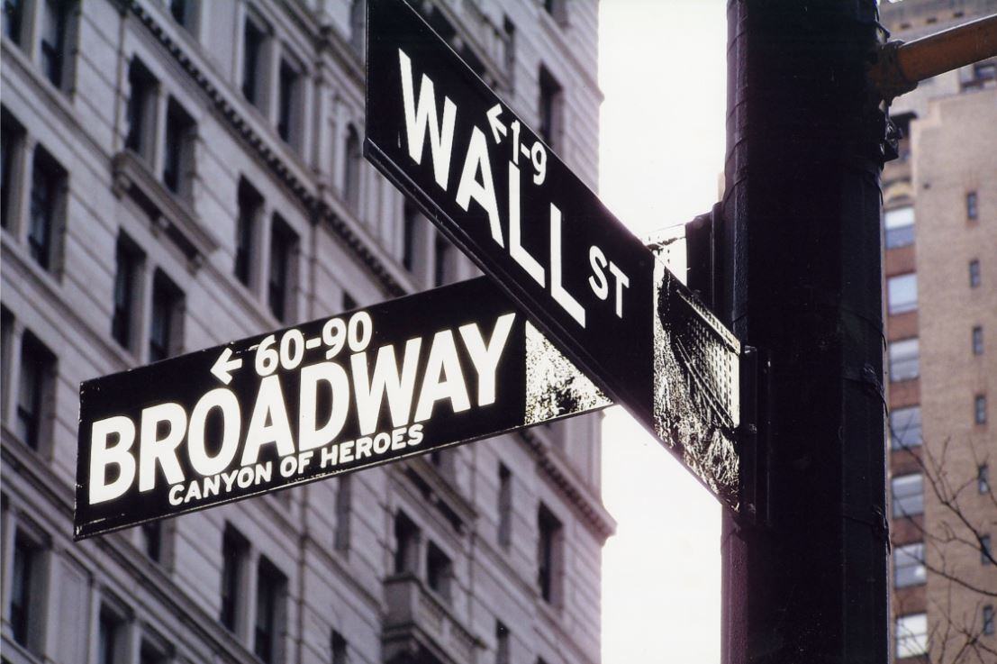 Black and white image of crossroad signs of Wall St and Broadway